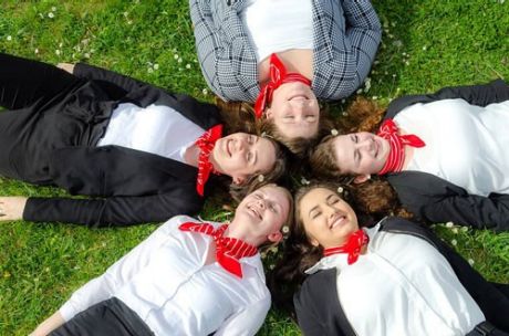 5 junge Auszubildende der Sparkasse Bodensee liegen lachend auf grüner Wiese