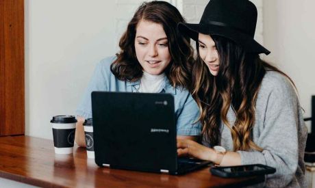Zwei junge Frauen schauen auf Laptop und lassen sich von der Sofort-Beratung der Sparkasse Bodensee beraten