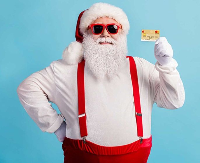 Weihnachtsmann mit roter Brille, der die Mastercard Gold (Kreditkarte) fürs Weihnachtsshopping empfiehlt