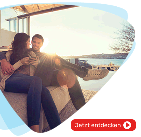 Junges Paar sitzt glücklich auf Sofa in Ihrem neuen Zuhause am Bodensee