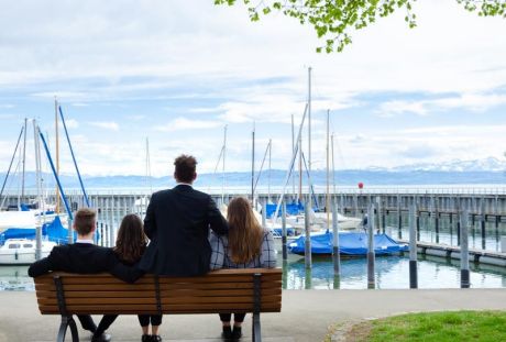 4 Auszubildende sitzen auf Parkbank und blicken auf den Yachthafen in Friedrichshafen