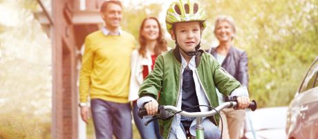 Eltern schauen Kind beim Fahrradfahren zu